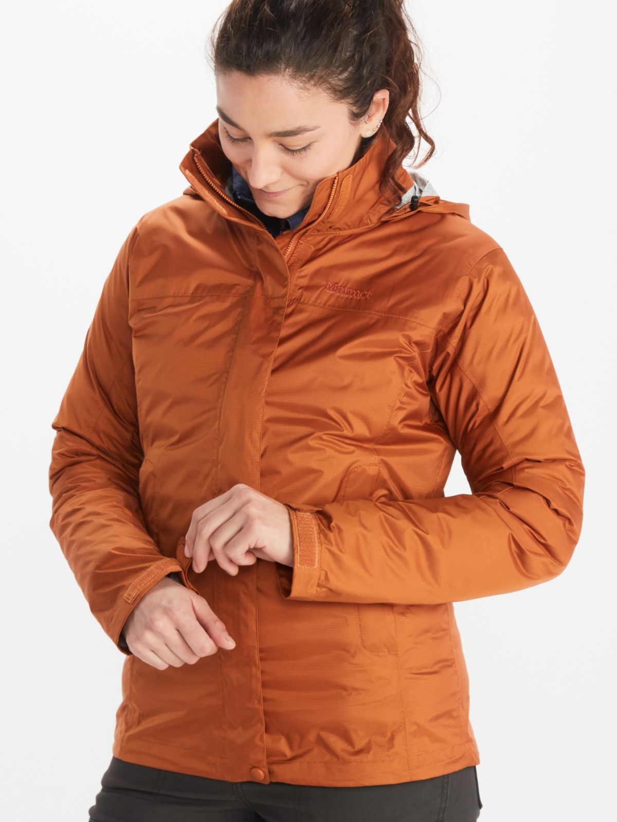 Woman adjusts velcro on the sleeve of her orange Marmot PreCip jacket