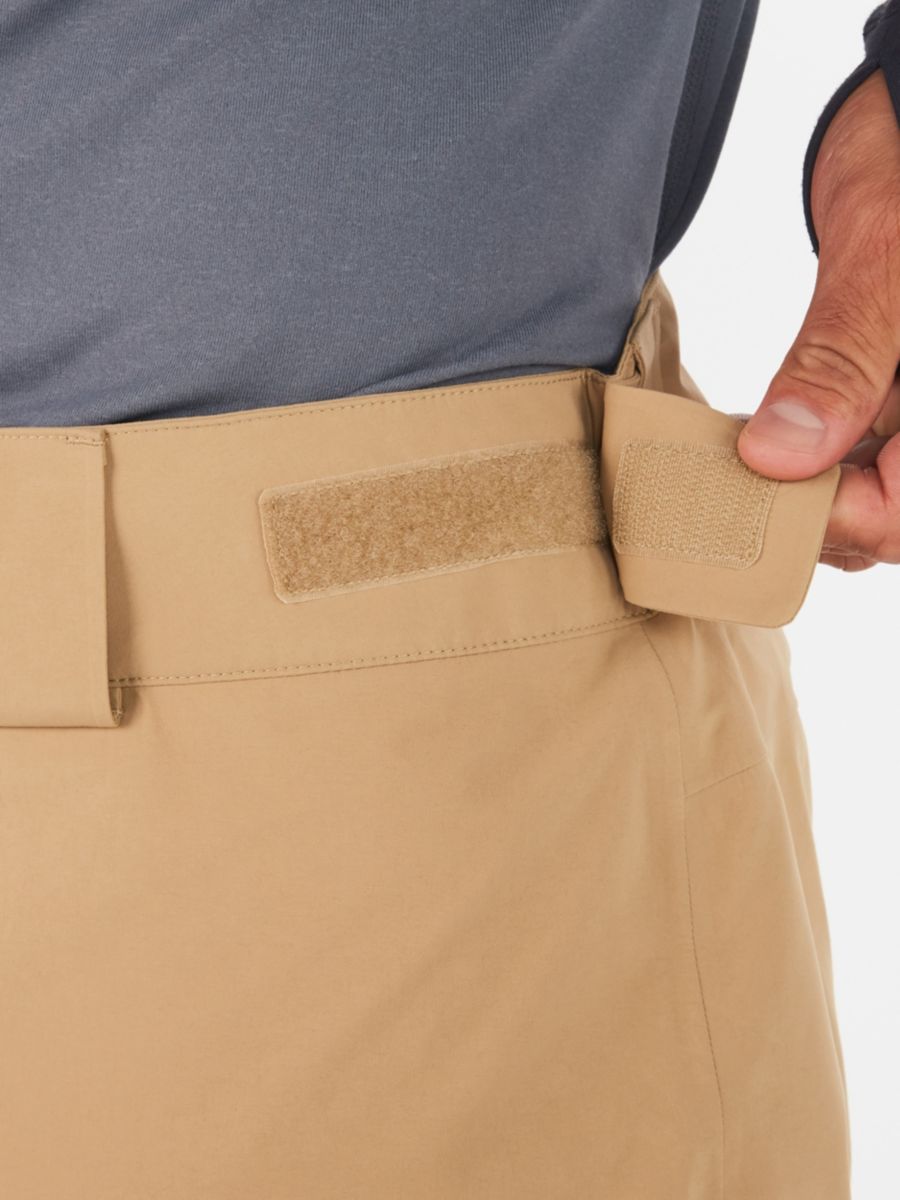 Model adjusting waistband of Marmot men's pants with hook and eye tabs