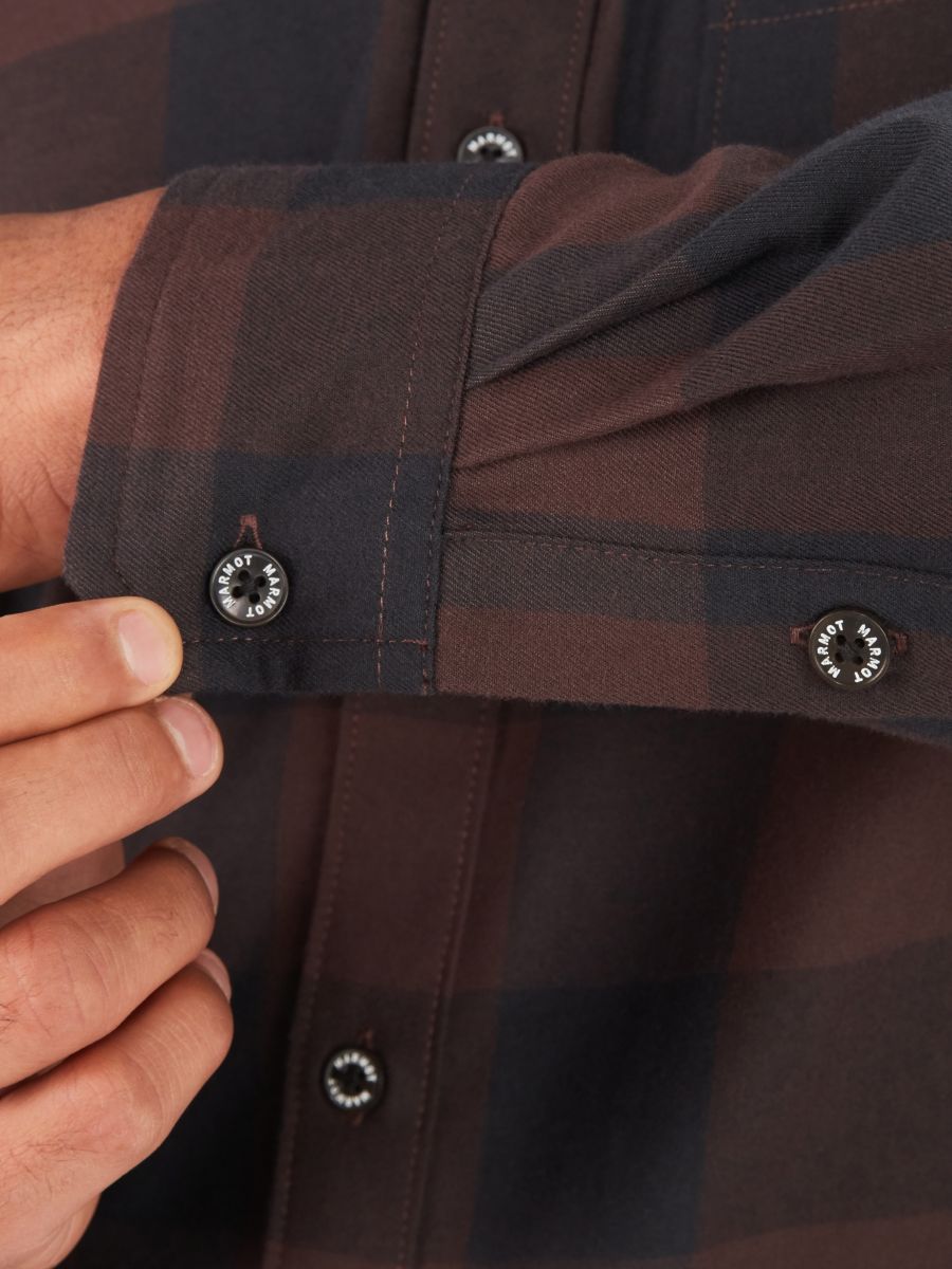 Model displaying buttoned cuff on Marmot men's long sleeve flannel shirt in brown plaid