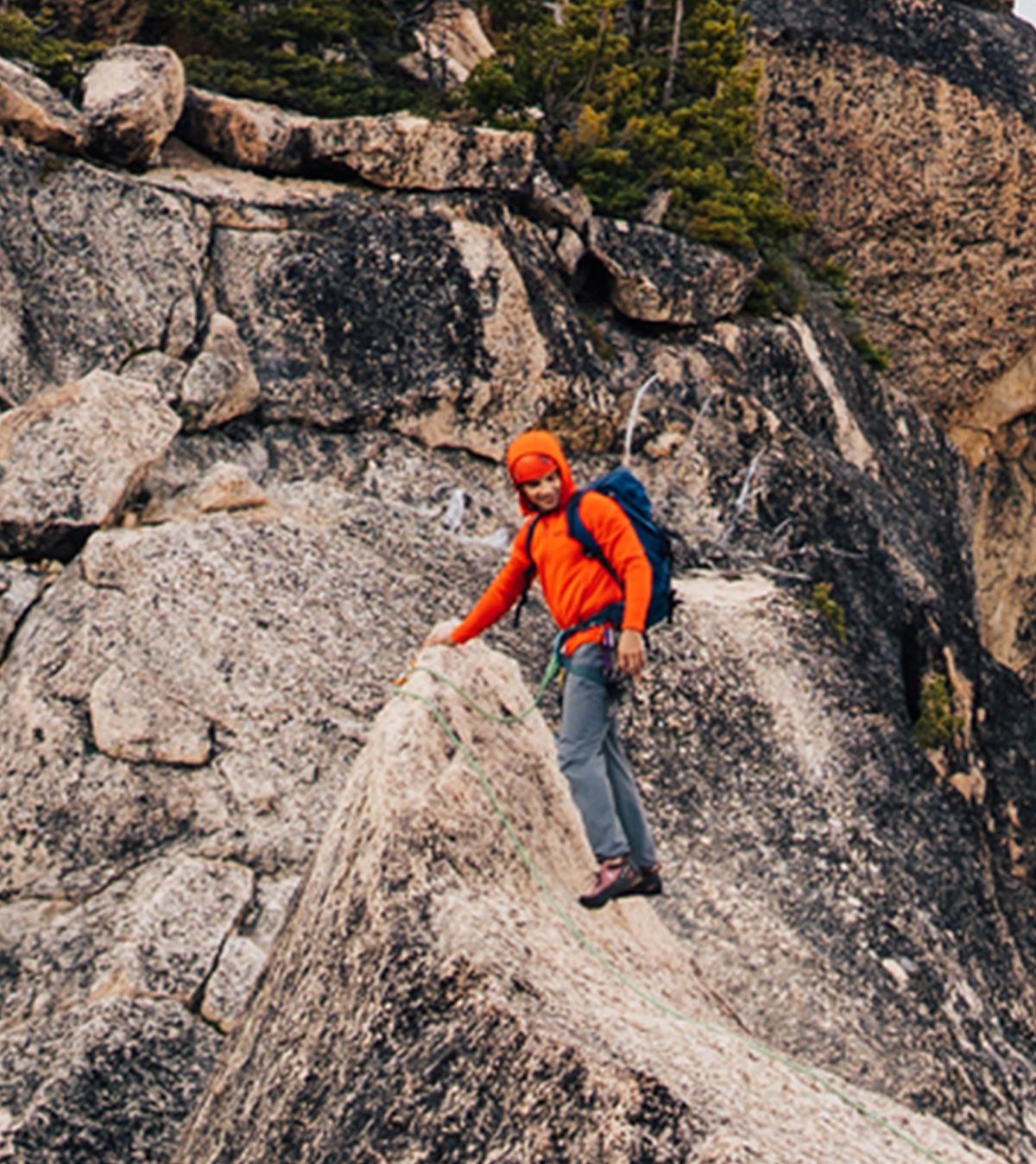 hiker on rocky terrain wearing orange jacket with hood