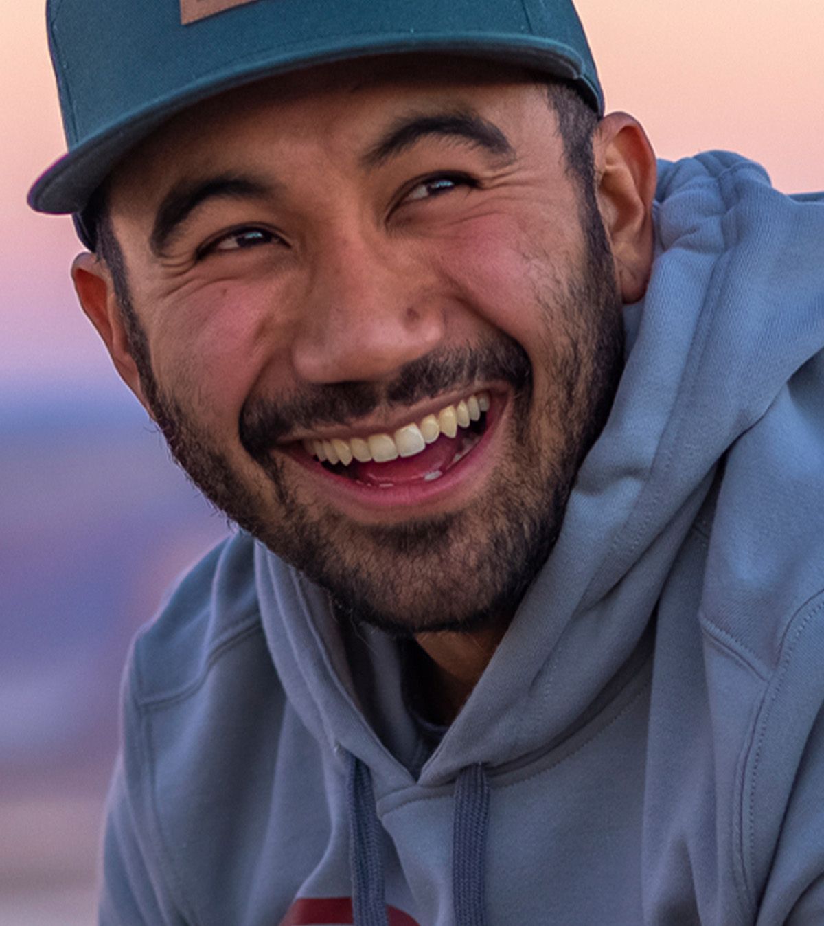 close up of smiling man wearing blue hoodie and hat