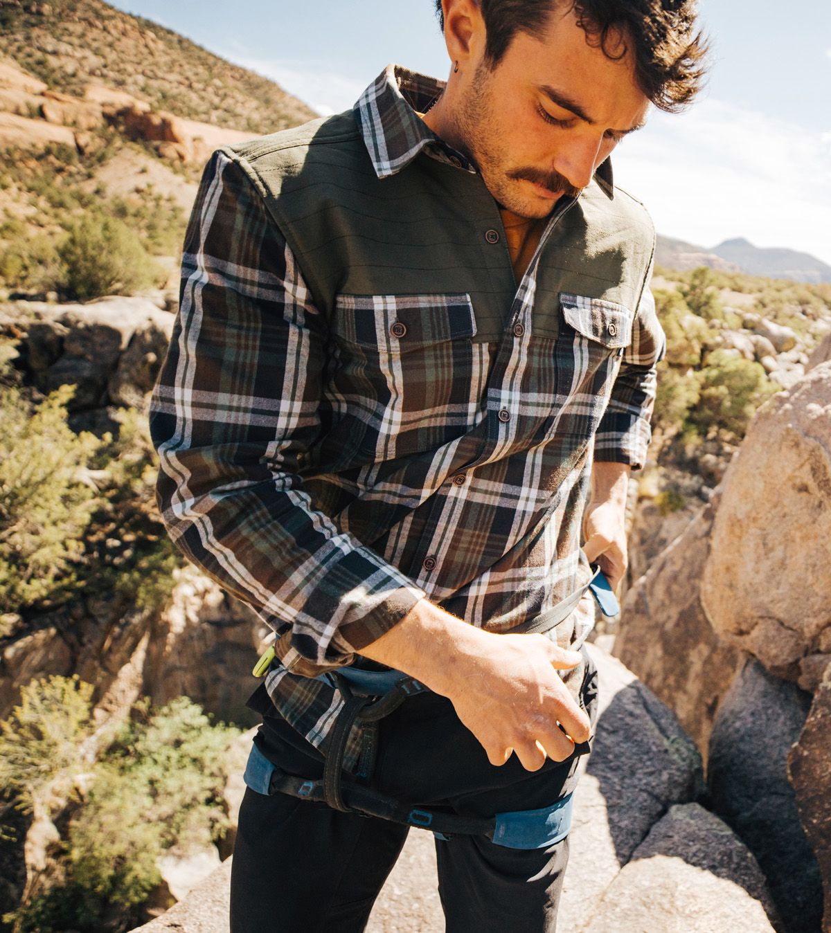 hiker on mountain wearing plaid shirt