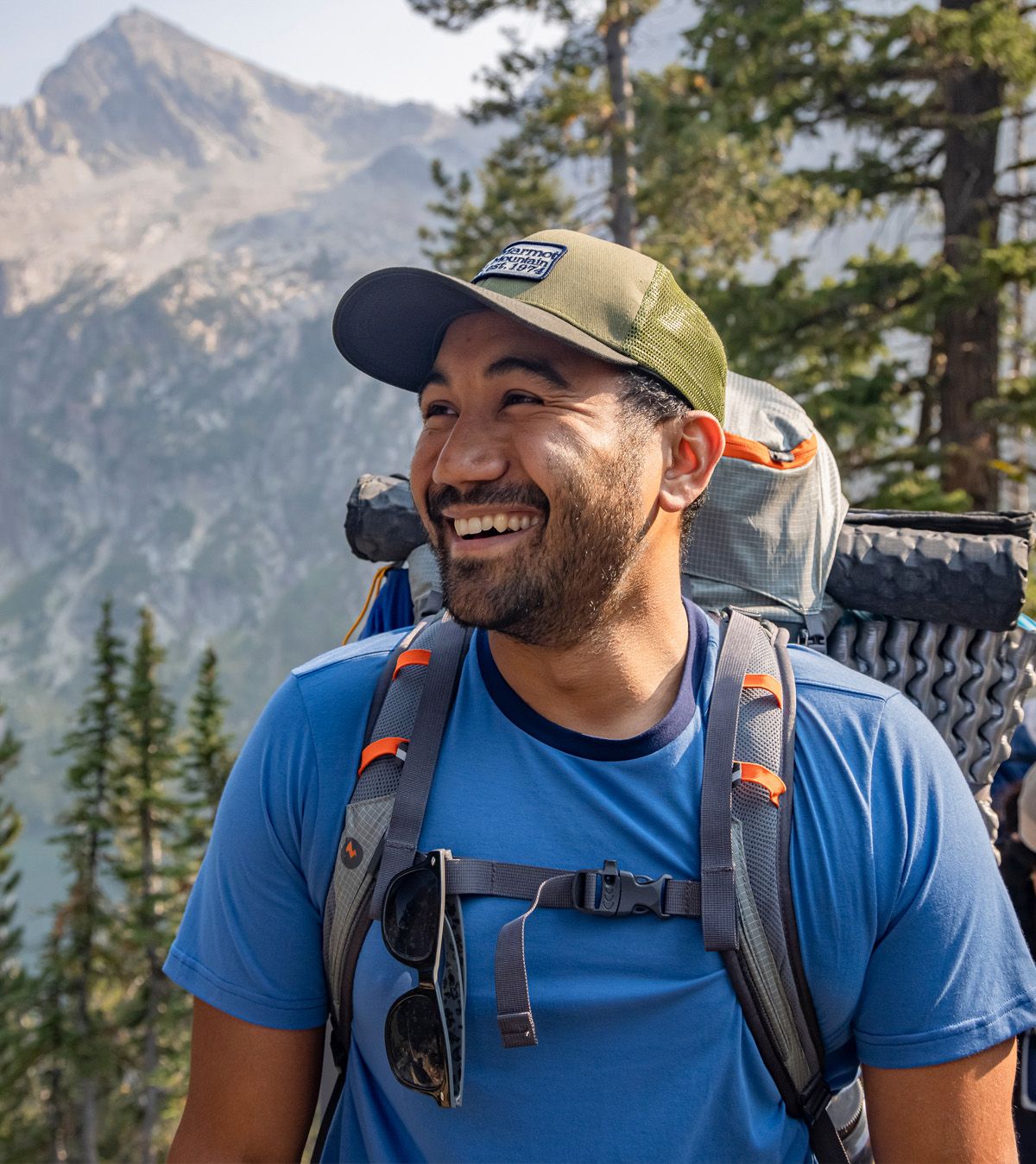 hiker on mountain wearing backpack and blue short sleeved shirt